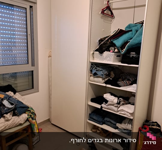 ארון בגדים פתוח עם בגדים מקופלים ונעליים על הרצפה